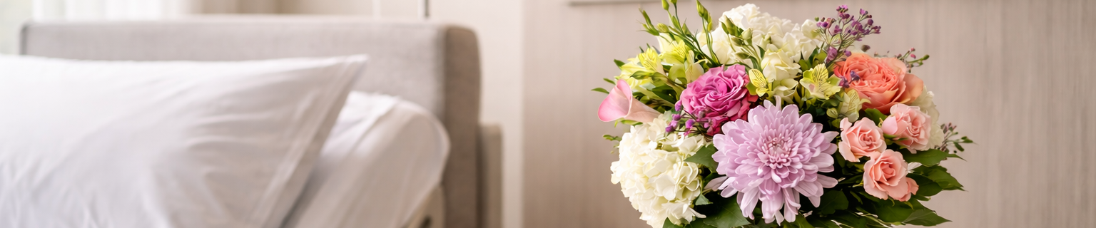 floral arrangement in a contemporary hospital room, featuring roses, hydrangeas and seasonal blooms in a clear glass vase,  Montreal flower delivery