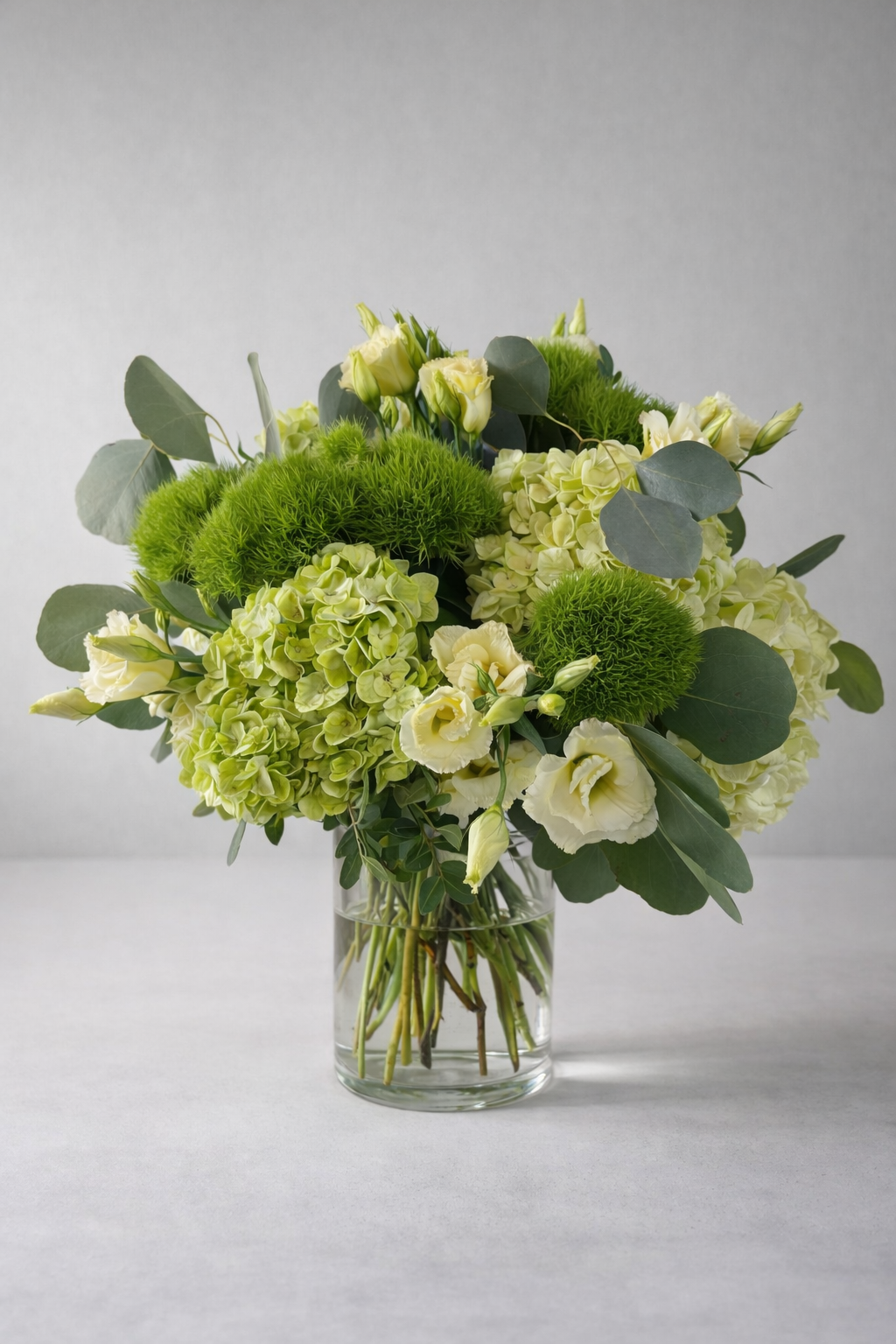 Green hydrangea and lisianthus arrangement in a clear vase by a Montreal florist
