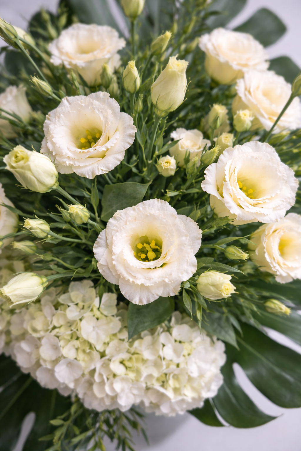 Top view of ivory lisianthus blooms and white hydrangeas with elegant foliage in a luxury floral arrangement from Montreal
