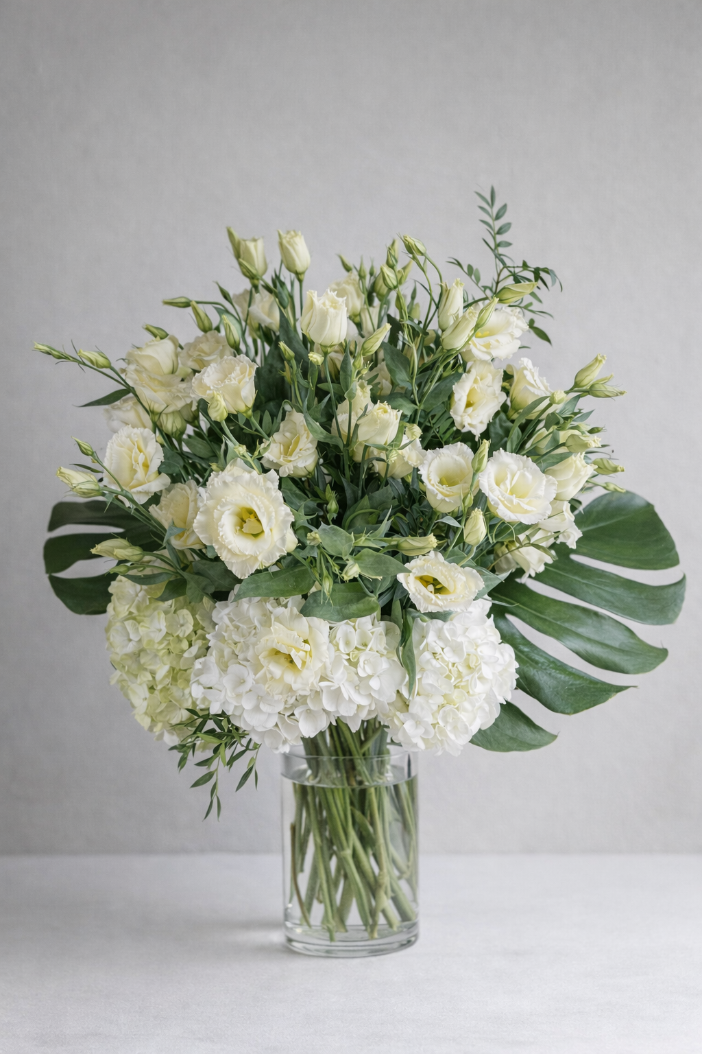 Ivory lisianthus and white hydrangea arrangement in a clear glass vase, designed by a Montreal florist
