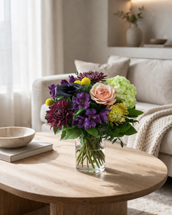Luxury floral arrangement in a clear glass vase styled in a cosy contemporary interior with soft natural light and neutral warm decor