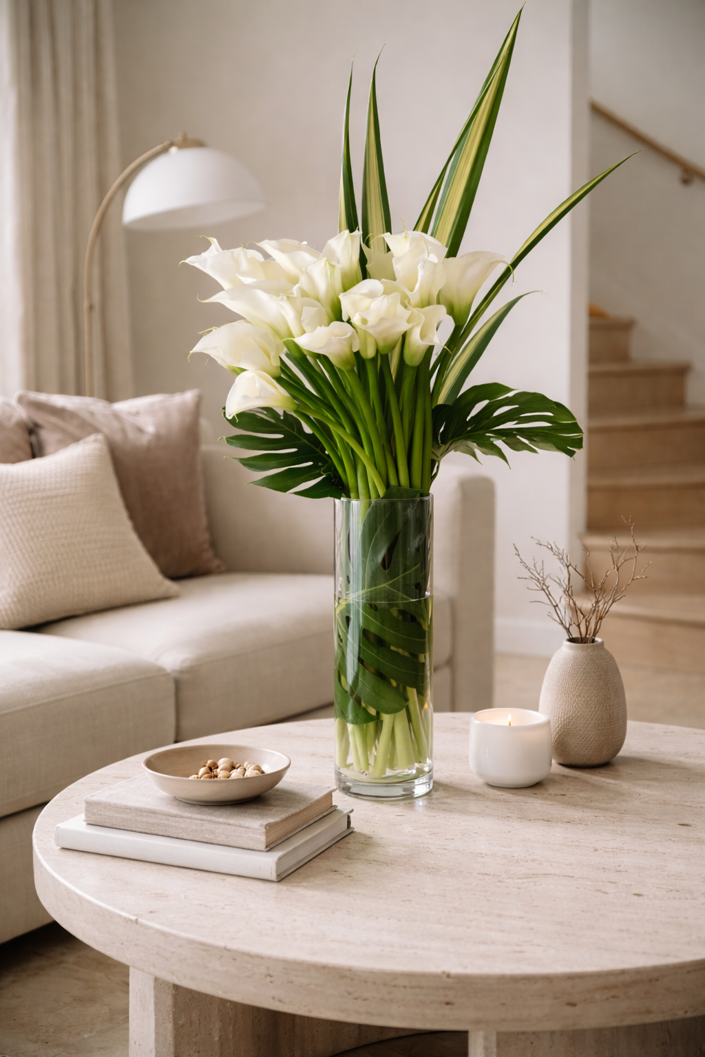 Large white calla lily bouquet styled in bright contemporary interior, high-end floral design in glass vase Montreal.