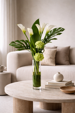 White calla lily and hydrangea arrangement in a slim clear vase styled in a warm contemporary interior, reflecting the polished aesthetic of a luxury florist Montreal.
