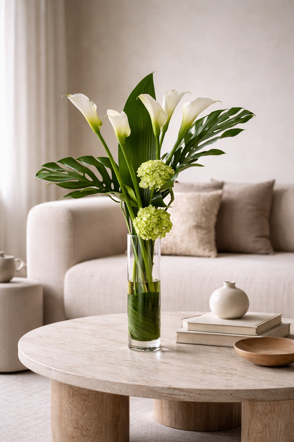 White calla lily and hydrangea arrangement in a slim clear vase styled in a warm contemporary interior, reflecting the polished aesthetic of a luxury florist Montreal.