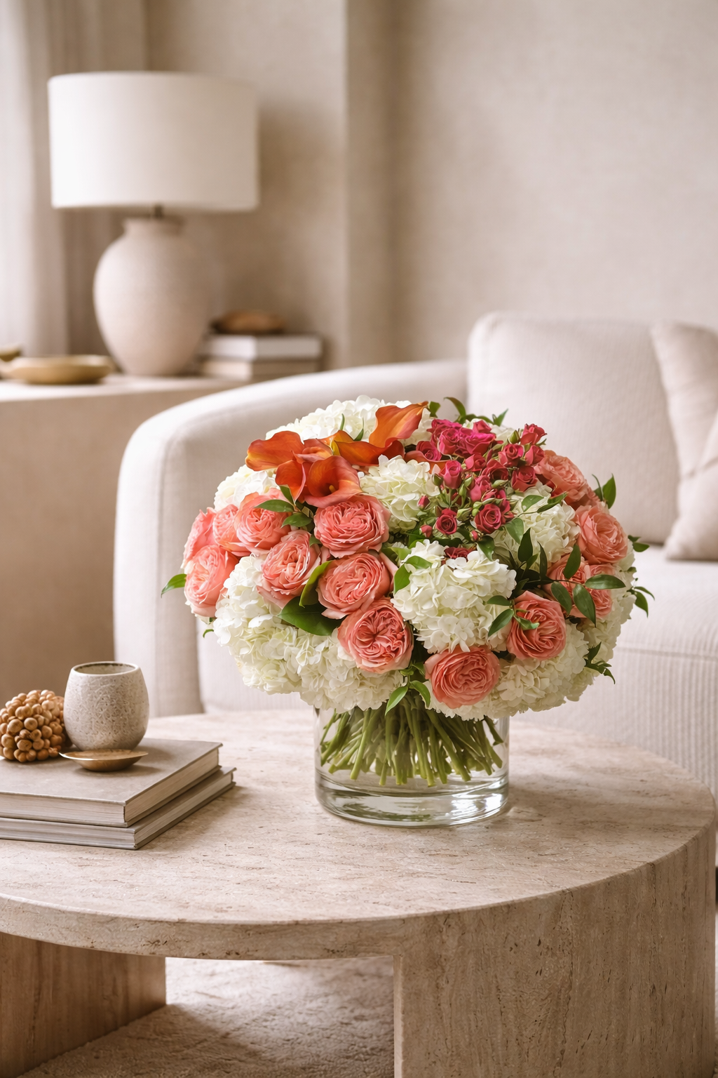 Luxury floral arrangement with coral garden roses, white hydrangeas, magenta spray roses, and orange calla lilies styled in a warm contemporary interior, suitable for a premium Montreal florist and flower delivery Montreal collection.