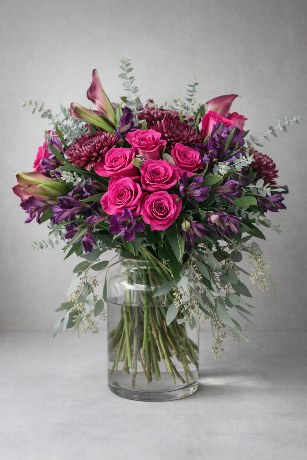 Luxury pink and purple rose bouquet in clear glass vase, editorial studio floral photography, Montreal flower delivery.
