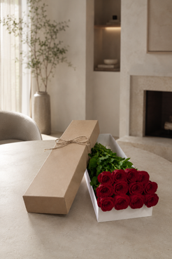 Contemporary floral gift box featuring twelve red roses, rich green foliage, and minimalist packaging, photographed with an upscale editorial finish for a premium Montreal florist