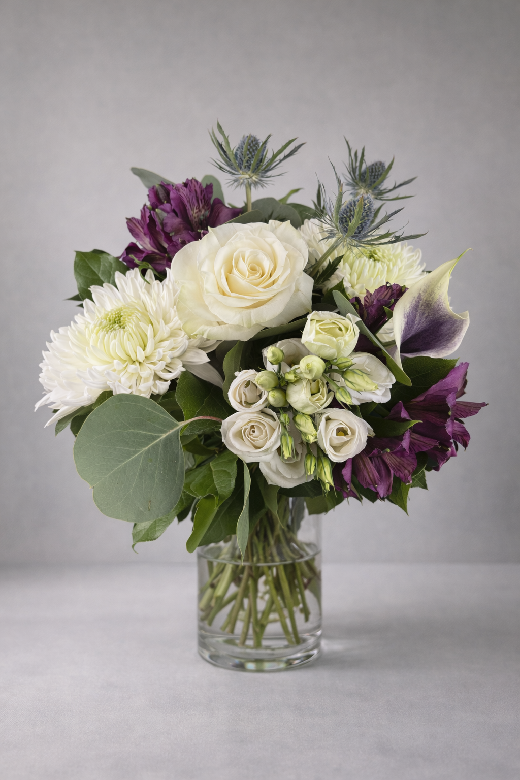Luxury white and purple flower bouquet in a clear glass vase by a Montreal florist