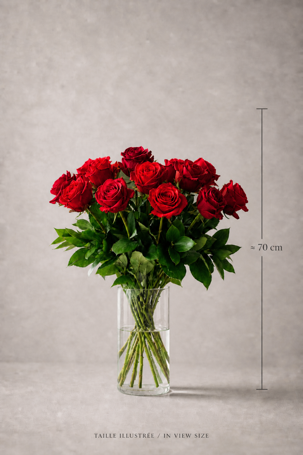 Premium bouquet of red Ecuador Freedom roses with rich green foliage in a clear glass vase, shown with a 70 cm size reference for scale in a refined editorial product image for flower delivery Montreal.