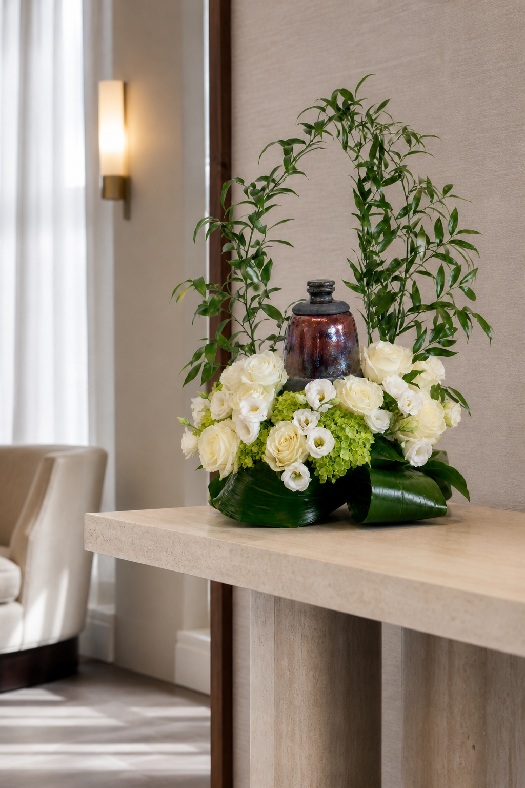 Luxury memorial floral arrangement with white roses, lisianthus, hydrangea and tall greenery displayed on a console in a serene contemporary interior, suitable for flower delivery Montreal.