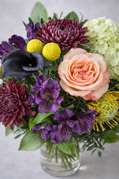 Top view floral detail of a luxury bouquet with peach rose, dark calla lily, purple alstroemeria, burgundy chrysanthemums and green hydrangea.
