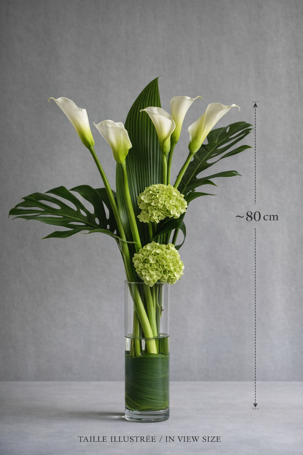 Luxury floral arrangement with white calla lilies, green hydrangeas, tropical foliage, and a clear cylinder vase shown with an approximate 80 cm size reference, suitable for premium bouquet Montreal searches.