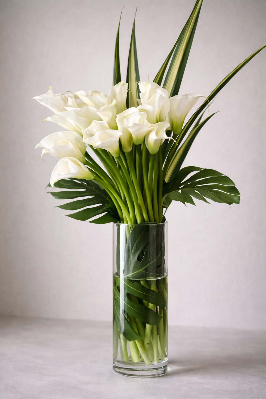 White calla lily bouquet 3/4 angle view, modern floral arrangement in clear glass vase, Montreal luxury florist design.